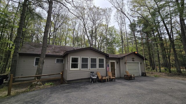 211 Skocelas Rd N, Manistee, MI 49660 - back of property featuring an attached garage, driveway, and roof with shingles