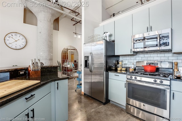 444 W Willis St Unit 211, Detroit, MI 48201 - kitchen featuring appliances with stainless steel finishes, finished concrete flooring, a high ceiling, backsplash, and dark stone counters