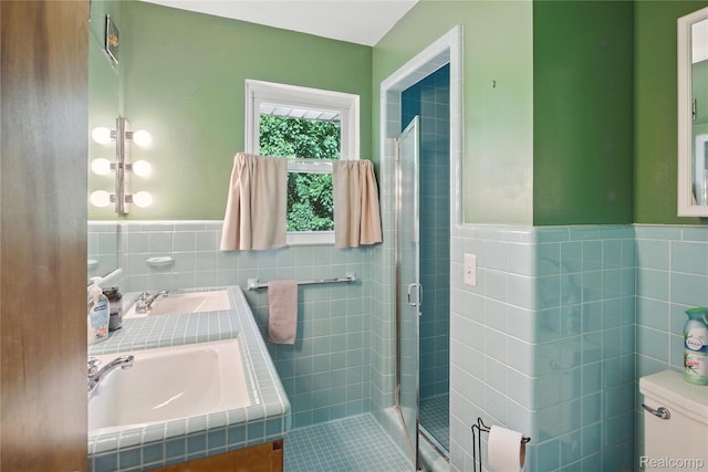 2329 Cumberland Rd, Lansing, MI 48906 - bathroom featuring tile walls, double vanity, a shower stall, wainscoting, and tile patterned floors