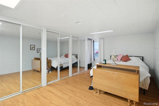 2329 Cumberland Rd, Lansing, MI 48906 - bedroom featuring multiple closets, wood finished floors, concrete block wall, and a fireplace