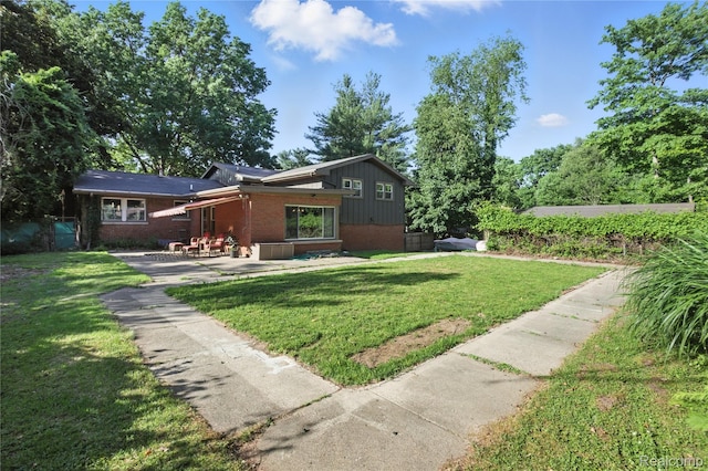 2329 Cumberland Rd, Lansing, MI 48906 - view of front of home featuring brick siding, a patio, and a front yard