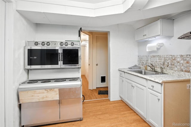 2329 Cumberland Rd, Lansing, MI 48906 - kitchen with light wood-style flooring, white cabinets, light countertops, and tasteful backsplash