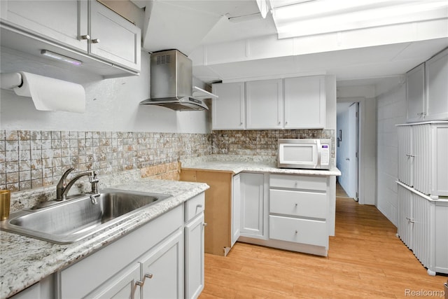 2329 Cumberland Rd, Lansing, MI 48906 - kitchen featuring white microwave, island range hood, decorative backsplash, and light wood-style flooring