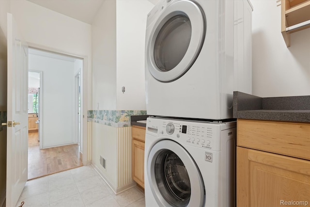 1921 Dunham Dr, Rochester, MI 48306 - washroom featuring stacked washer and clothes dryer, cabinet space, and light tile patterned floors