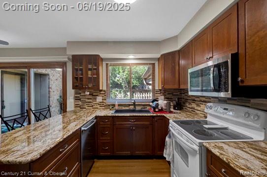 7190 Pebble Park Dr, West Bloomfield, MI 48322 - kitchen with stainless steel appliances, a peninsula, light stone counters, and backsplash