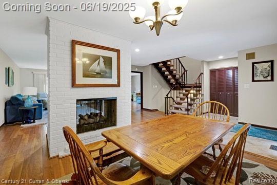 7190 Pebble Park Dr, West Bloomfield, MI 48322 - dining area featuring a chandelier, wood finished floors, stairs, a brick fireplace, and recessed lighting