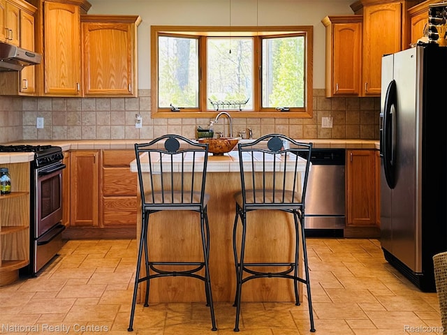 1390 N US-23, East Tawas, MI 48730 - kitchen featuring appliances with stainless steel finishes, tile counters, healthy amount of natural light, and a kitchen island