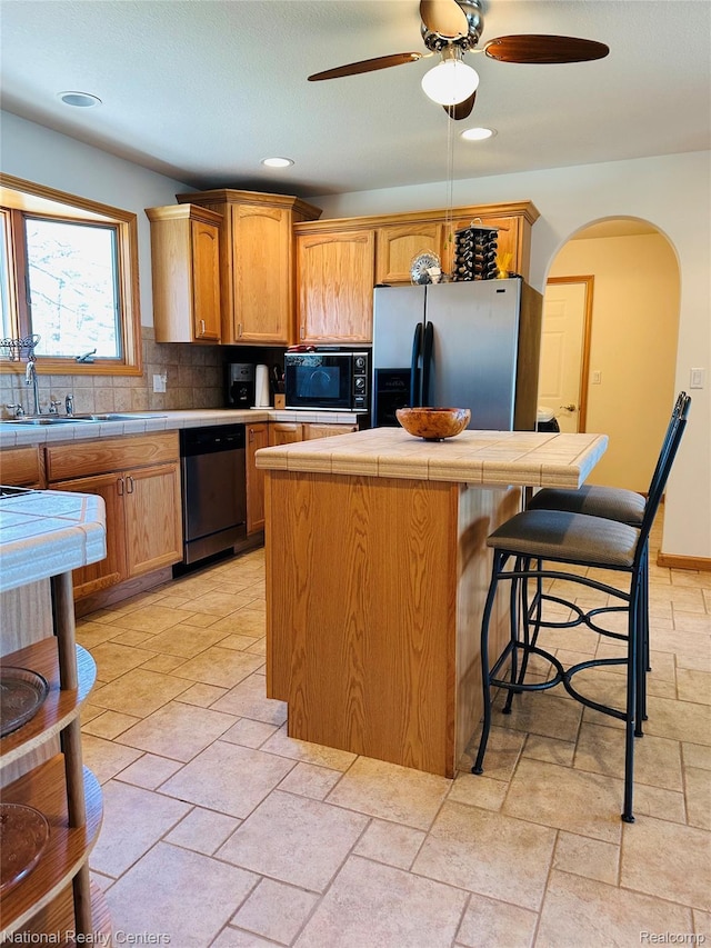 1390 N US-23, East Tawas, MI 48730 - kitchen featuring appliances with stainless steel finishes, tile countertops, a center island, a ceiling fan, and recessed lighting
