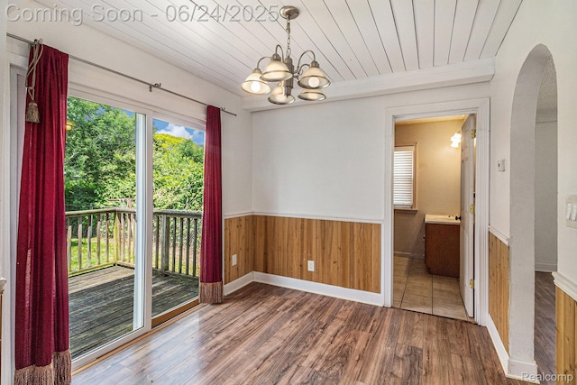 2061 E Boatfield Ave, Burton, MI 48529 - unfurnished dining area with arched walkways, wood finished floors, a chandelier, wainscoting, and wooden walls