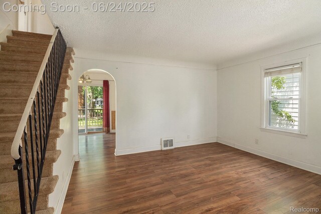 2061 E Boatfield Ave, Burton, MI 48529 - empty room featuring dark wood finished floors, a textured ceiling, stairway, and arched walkways