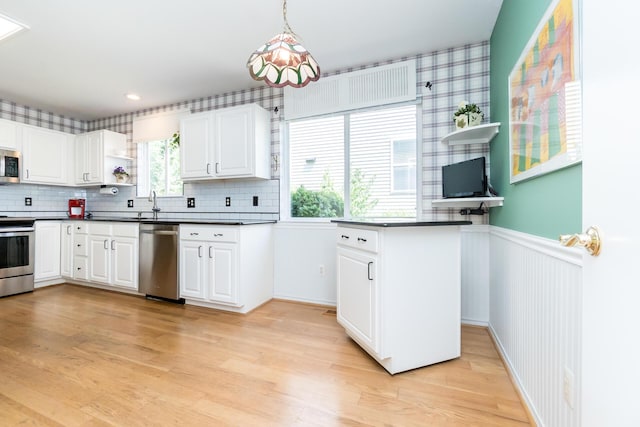 3105 Earlmoore Ln, Ann Arbor, MI 48105 - kitchen with stainless steel appliances, dark countertops, light wood-type flooring, a wainscoted wall, and white cabinets