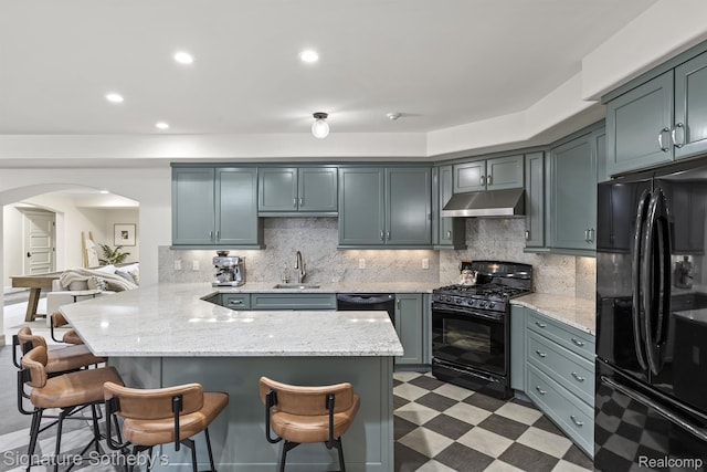 597 Yarboro Dr, Bloomfield Hills, MI 48304 - kitchen with black appliances, arched walkways, a kitchen bar, under cabinet range hood, and light flooring