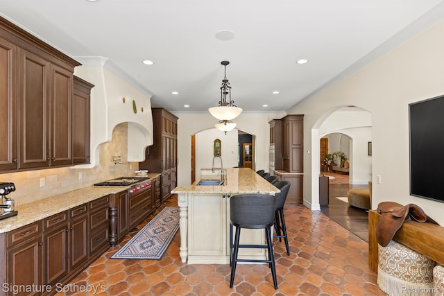597 Yarboro Dr, Bloomfield Hills, MI 48304 - kitchen with arched walkways, backsplash, light stone countertops, a breakfast bar, and stainless steel gas stovetop