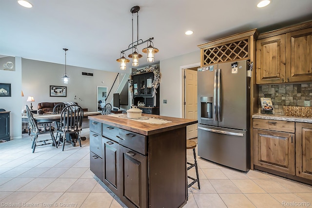 1355 Maxfield Rd, Brighton, MI 48114 - kitchen featuring stainless steel refrigerator with ice dispenser, wood counters, light tile patterned floors, backsplash, and a kitchen bar