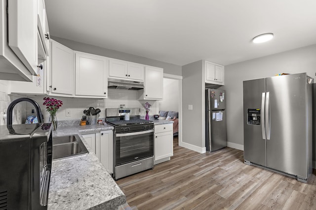 645 Amity Ave, Muskegon, MI 49442 - kitchen featuring stainless steel appliances, under cabinet range hood, light countertops, light wood-type flooring, and backsplash