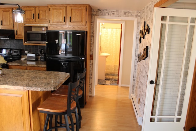 7680 S Warner Ave, Fremont, MI 49412 - kitchen featuring black appliances, light wood finished floors, a kitchen bar, tasteful backsplash, and wallpapered walls