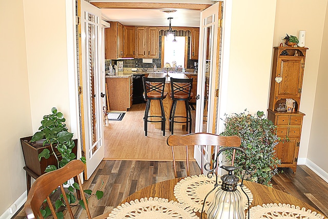 7680 S Warner Ave, Fremont, MI 49412 - kitchen with dark wood-style floors, brown cabinetry, light countertops, hanging light fixtures, and backsplash