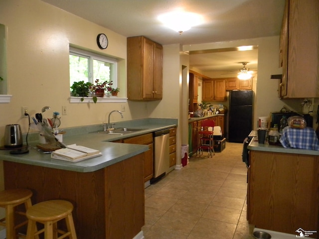 6864 Hazeldell Dr, Temperance, MI 48182 - kitchen with freestanding refrigerator, a peninsula, a ceiling fan, a breakfast bar, and brown cabinetry