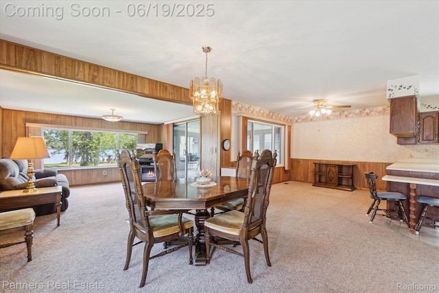 8331 Hilton Rd, Brighton, MI 48114 - dining space featuring light colored carpet, wooden walls, a chandelier, and ceiling fan