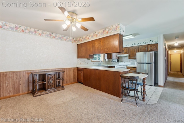 8331 Hilton Rd, Brighton, MI 48114 - kitchen featuring white appliances, a peninsula, light countertops, ceiling fan, and brown cabinetry