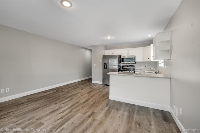 1545 W 9 Mile Rd, Ferndale, MI 48220 - kitchen with stainless steel appliances, open shelves, white cabinetry, wood finished floors, and a peninsula