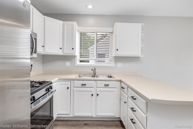 1545 W 9 Mile Rd, Ferndale, MI 48220 - kitchen with appliances with stainless steel finishes, white cabinetry, light countertops, a peninsula, and recessed lighting
