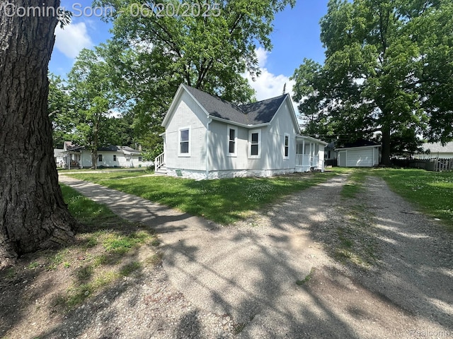 101 Morrell St, Yale, MI 48097 - view of front of home with dirt driveway, a shingled roof, an outdoor structure, a front lawn, and a garage