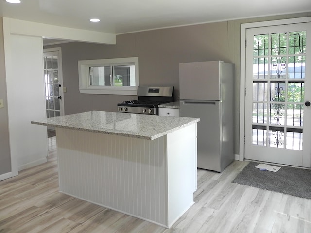 26370 S Shore Dr, Mendon, MI 49072 - kitchen with stainless steel range with gas cooktop, freestanding refrigerator, light wood finished floors, a center island, and light stone countertops
