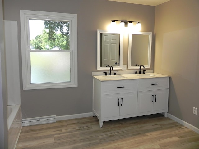 26370 S Shore Dr, Mendon, MI 49072 - bathroom with double vanity, a baseboard radiator, wood finished floors, and a bathtub