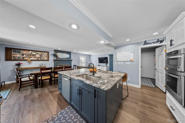 8206 Saint James Ct, Grosse Ile, MI 48138 - kitchen featuring ornamental molding, appliances with stainless steel finishes, white cabinetry, an island with sink, and dark wood finished floors