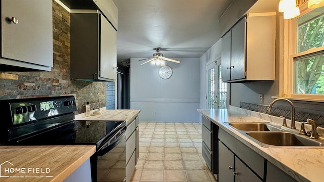 713 Wiltshire Dr, Owosso, MI 48867 - kitchen with black electric range, a ceiling fan, and light stone finish flooring