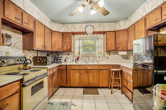 52 Roseneath Ave, Battle Creek, MI 49037 - kitchen with white electric stove, freestanding refrigerator, ceiling fan, and brown cabinetry
