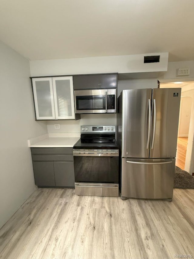 2130 Geneva St, Dearborn, MI 48124 - kitchen with stainless steel appliances, light wood-style floors, light countertops, glass insert cabinets, and gray cabinets