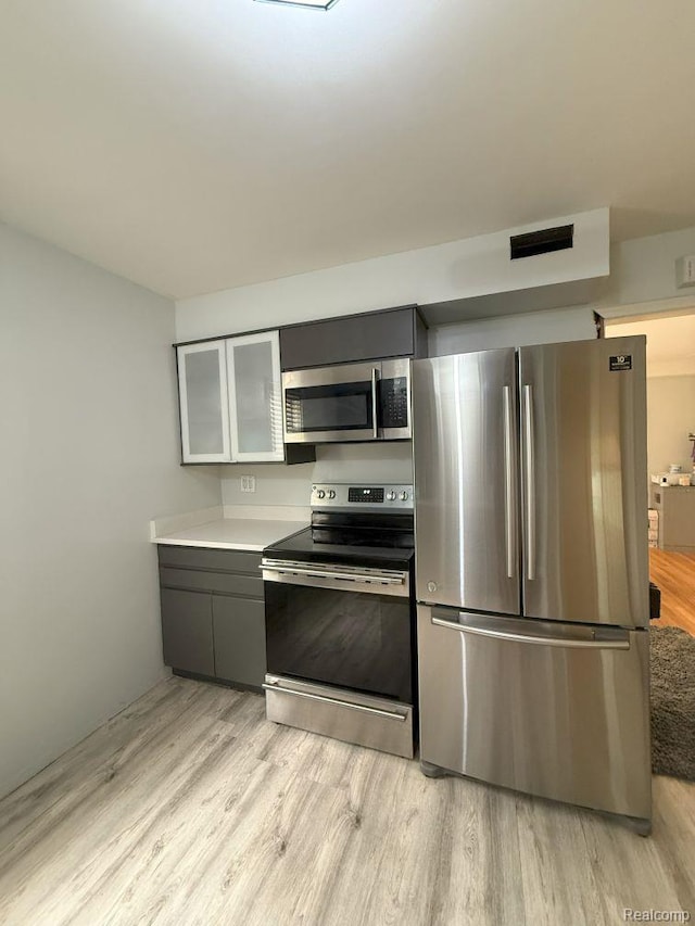 2130 Geneva St, Dearborn, MI 48124 - kitchen featuring appliances with stainless steel finishes, light wood-style flooring, glass insert cabinets, light countertops, and gray cabinets