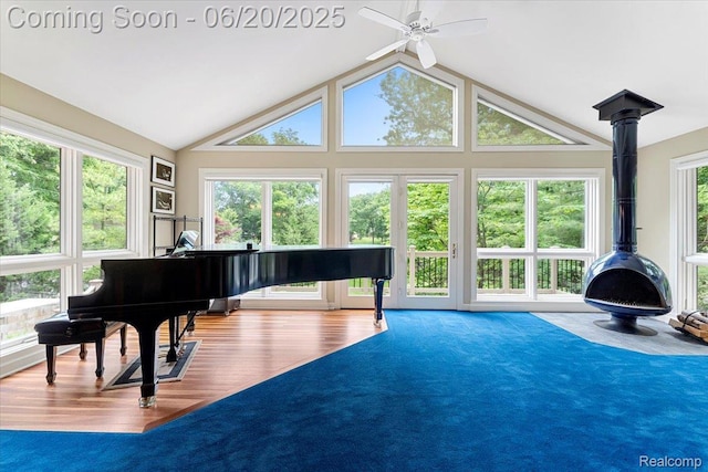 21089 Thorofare Rd, Grosse Ile, MI 48138 - living area featuring a ceiling fan, a wood stove, wood finished floors, and vaulted ceiling