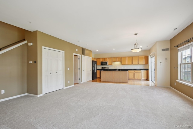 3207 Camden Dr Unit 110, Troy, MI 48084 - kitchen featuring black refrigerator with ice dispenser, open floor plan, dark countertops, stainless steel microwave, and light colored carpet