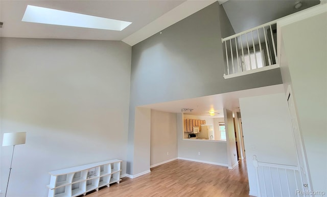157 E Bay Dr, Walled Lake, MI 48390 - unfurnished living room featuring a skylight, high vaulted ceiling, and light wood-type flooring