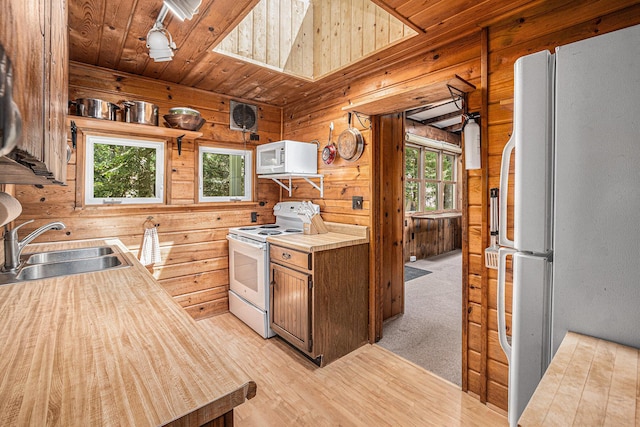 8641 N Perry Ave, Pentwater, MI 49449 - kitchen featuring white appliances, wooden walls, light wood-type flooring, wood ceiling, and light countertops