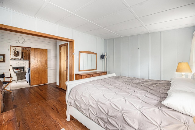 8641 N Perry Ave, Pentwater, MI 49449 - bedroom featuring wood-type flooring, a decorative wall, and a brick fireplace