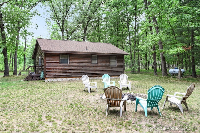9210/9228 S Star Lake Dr, Baldwin, MI 49304 - back of house featuring a fire pit, a lawn, a shingled roof, and log veneer siding