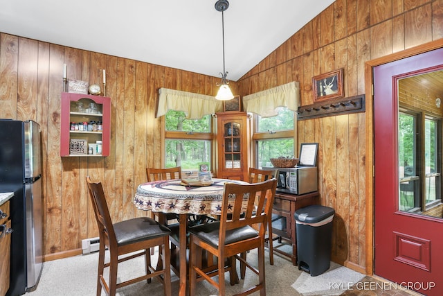 9210/9228 S Star Lake Dr, Baldwin, MI 49304 - dining room featuring healthy amount of natural light, vaulted ceiling, wood walls, carpet flooring, and a baseboard heating unit