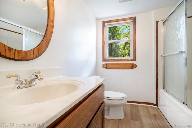 332 Community Dr, Battle Creek, MI 49014 - bathroom featuring vanity, wood finished floors, and combined bath / shower with glass door