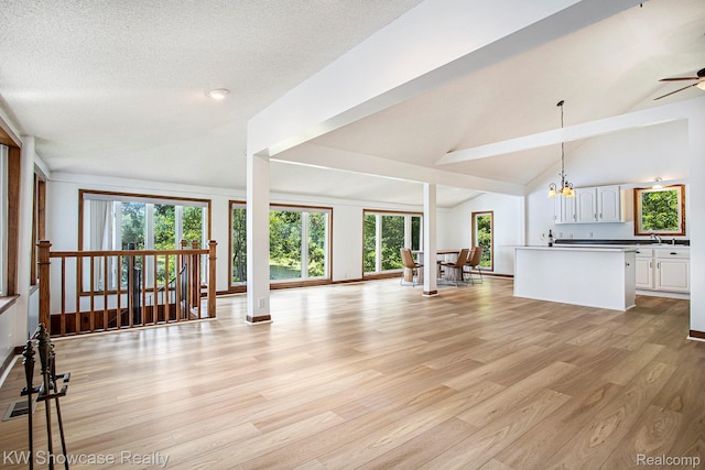 332 Community Dr, Battle Creek, MI 49014 - unfurnished living room with a chandelier, light wood finished floors, ceiling fan, and high vaulted ceiling
