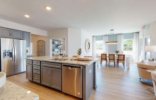 50260 Cromwell St, Canton, MI 48188 - kitchen featuring appliances with stainless steel finishes, light wood-style floors, light stone countertops, a center island with sink, and gray cabinetry
