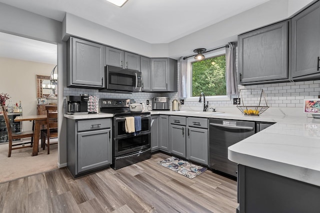 2062 Wildwood Trl, Saline, MI 48176 - kitchen with appliances with stainless steel finishes, gray cabinets, light wood-type flooring, light countertops, and tasteful backsplash
