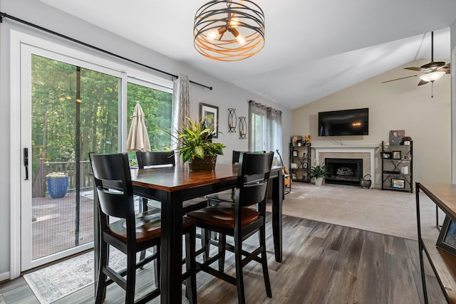 2062 Wildwood Trl, Saline, MI 48176 - dining area featuring lofted ceiling, a fireplace, dark wood-style floors, ceiling fan, and a chandelier