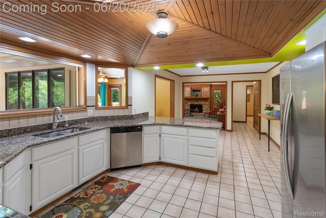 1484 Kings Pointe Rd, Grand Blanc, MI 48439 - kitchen featuring stainless steel appliances, wooden ceiling, light tile patterned floors, white cabinetry, and a warm lit fireplace