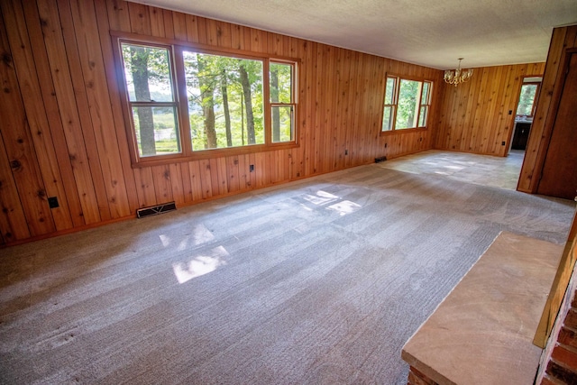 5774 N Wayne Ave, Pentwater, MI 49449 - carpeted spare room featuring a chandelier, wood walls, and a textured ceiling