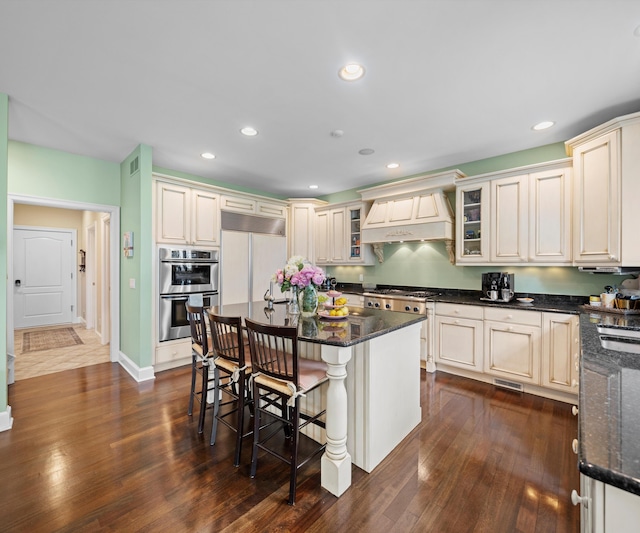 5011 Rockaway Ln, Clarkston, MI 48348 - kitchen with appliances with stainless steel finishes, premium range hood, a breakfast bar area, recessed lighting, and dark wood finished floors