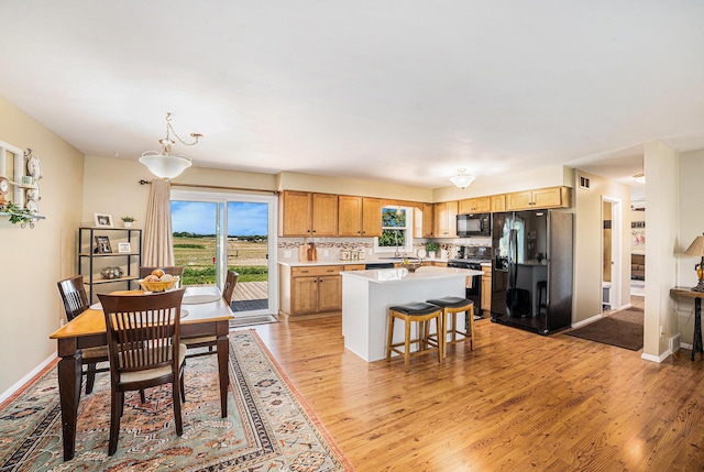 4515 S Lincoln Rd, Mount Pleasant, MI 48858 - kitchen featuring black appliances, light wood finished floors, a kitchen island, light countertops, and a kitchen bar
